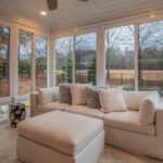 Spacious sunroom with contemporary sofa and large windows offering a serene outdoor view.