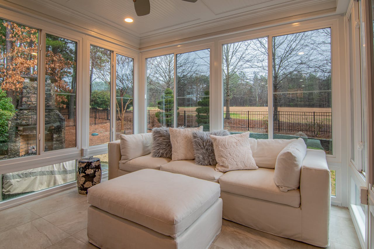 Spacious sunroom with contemporary sofa and large windows offering a serene outdoor view.