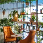 Inviting café corner with lush plants and cozy seating, perfect for relaxation.